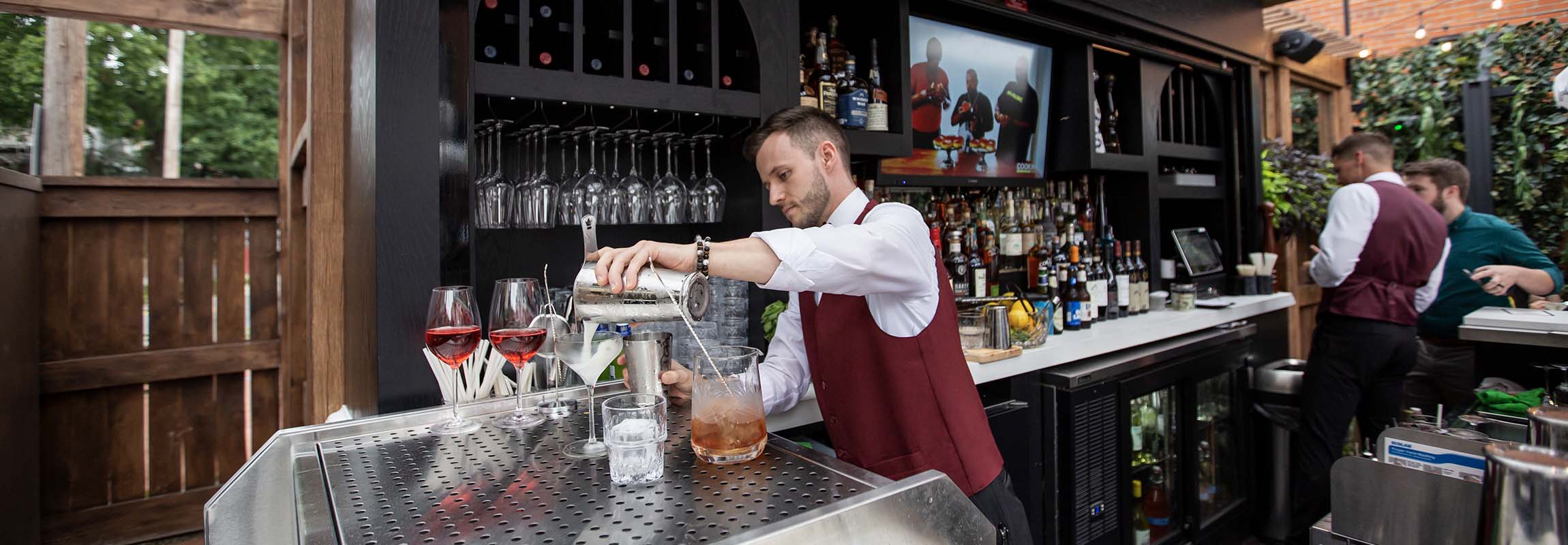 Bar chef pouring a just-shaken cocktail into a glass in the Terrazzo bar at Cento Italian restaurant in German Village.